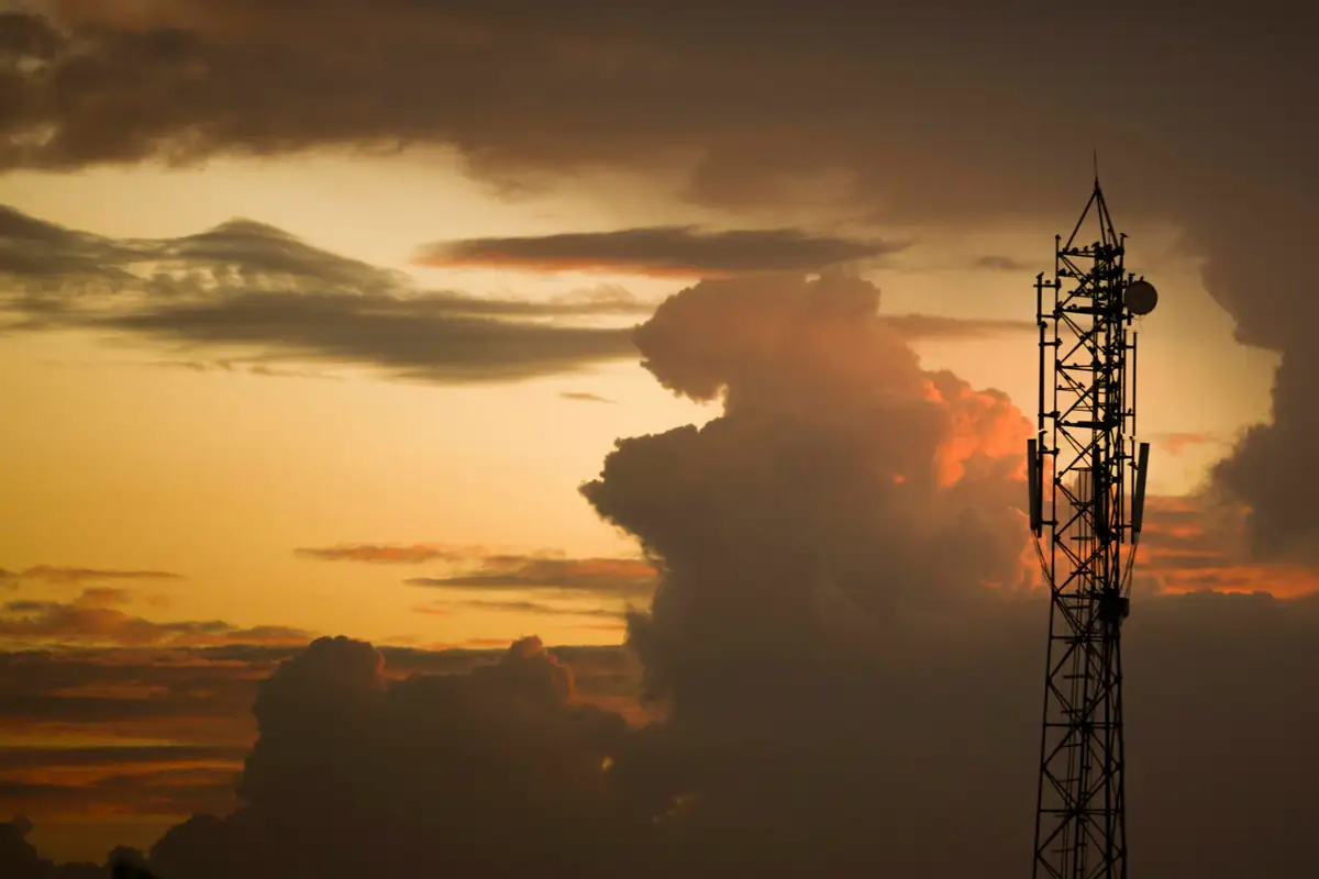 Torre de comunicação contra as nuvens no fim da tarde